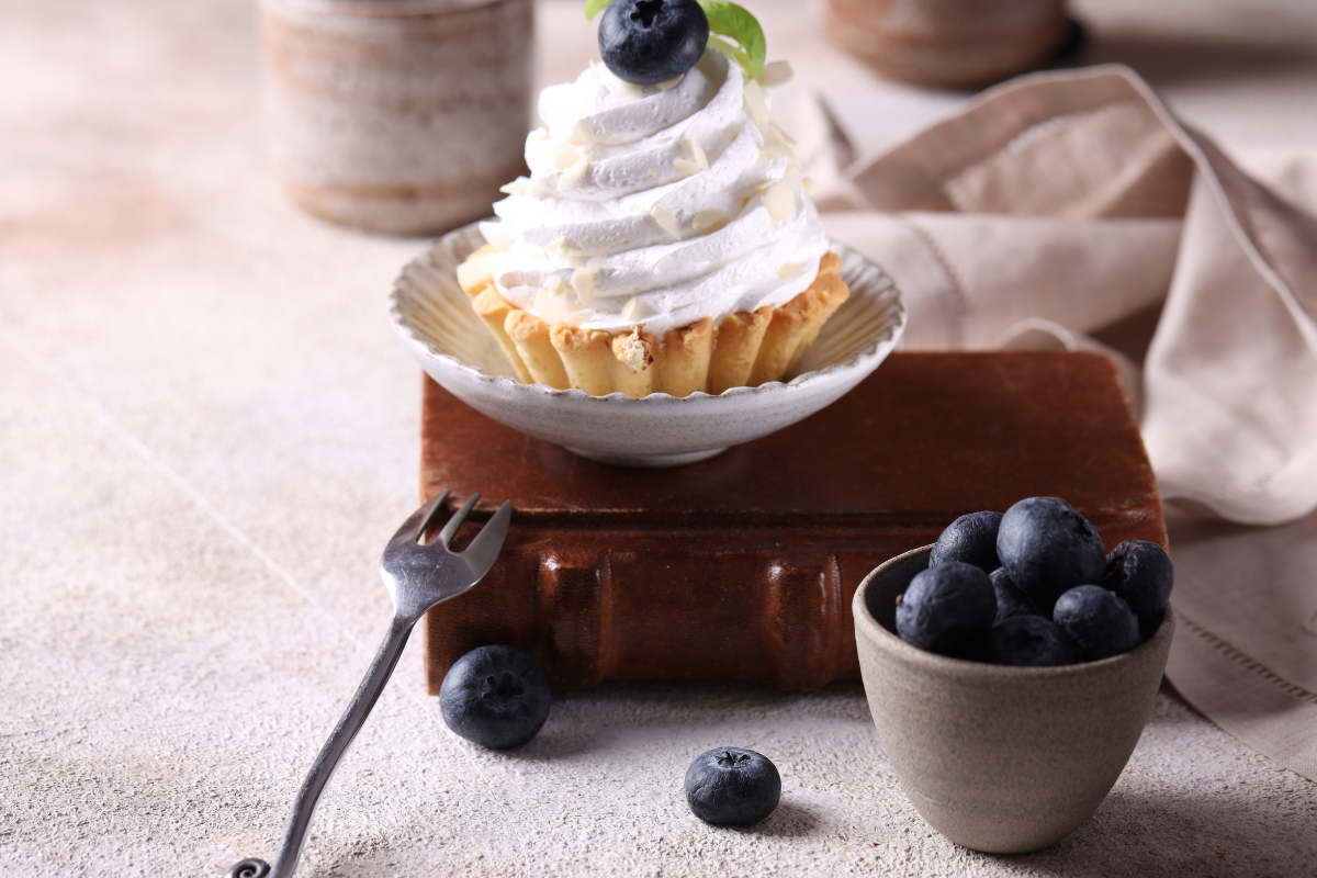 A vibrant fruit basket cake adorned with an assortment of fresh berries, kiwi, and citrus slices on a decorative stand.