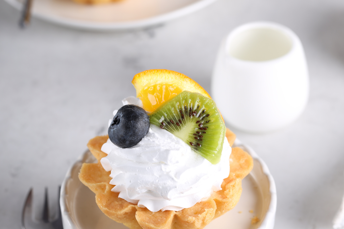 Close-up of a fruit basket cake showcasing its colorful fruit topping and fluffy sponge layers.