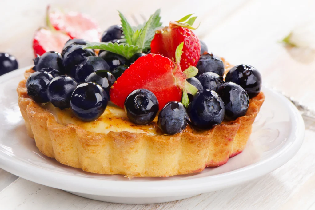 Elegantly presented fruit basket cake with a variety of meticulously arranged fresh fruits on a creamy frosting.
