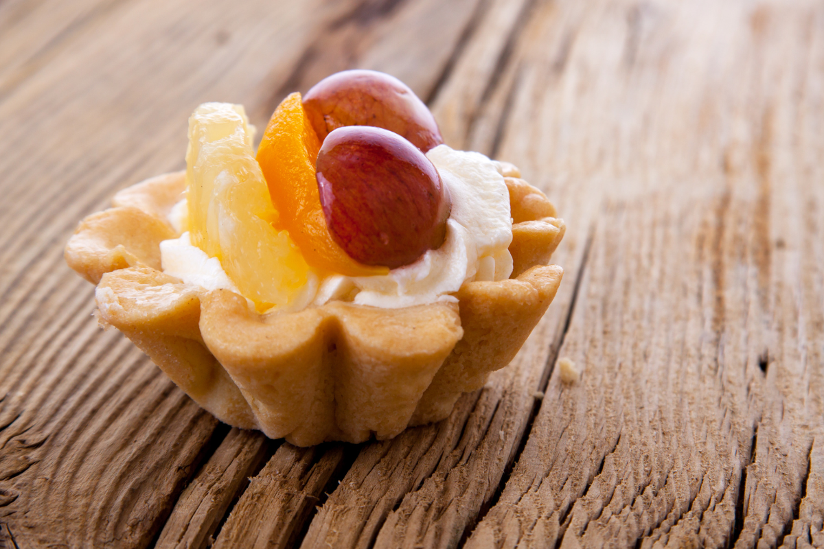 Artistic composition of a fruit basket cake, highlighting the contrast of the rich, colorful fruits against the soft, white cream.